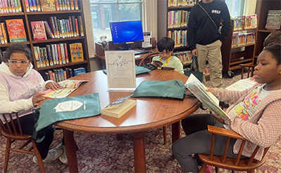 Students enjoying books at a table in the local library