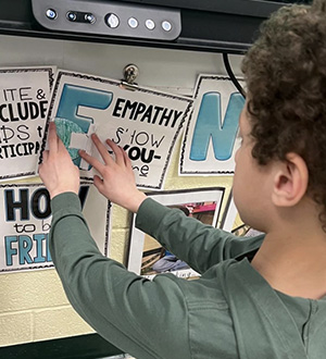A boy putting a paper butterfly on signs