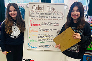 Two students standing next to a whiteboard about Context Clues