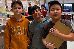 Three students, one is holding a clipboard