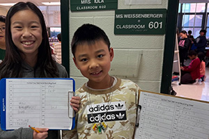 Two students, one is showing a clipboard