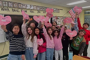 Students holding up pink paper hearts