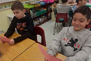 Two students smiling as they read their paper hearts