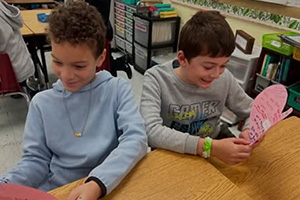 Two students reading paper hearts