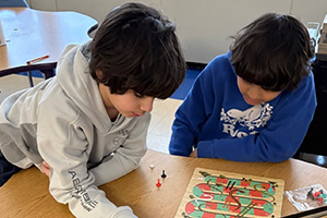 Two students at a table playing a board game