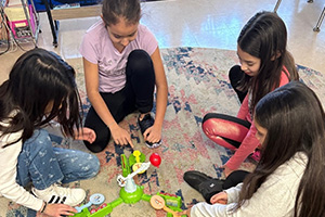 Four students playing a game on the floor