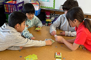 Four students playing a card game at a table