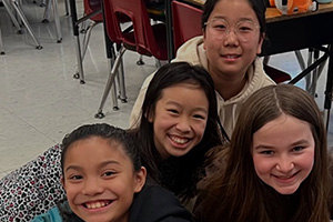 Four students sitting together and smiling