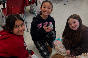 Three students playing cards on the floor