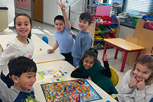 Six students playing a game with a colorful board