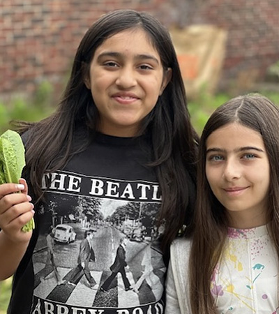 Two students smiling. One is holding lettuce