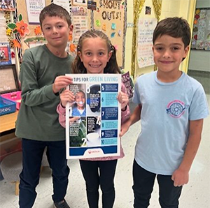 Three 4th graders holding a chart about green living