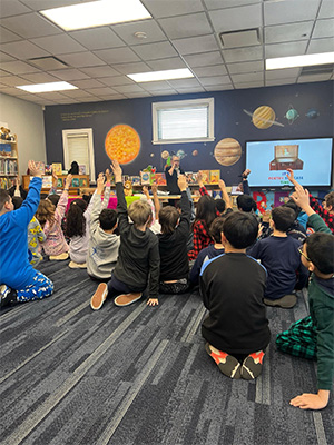 students raising their hands in a library